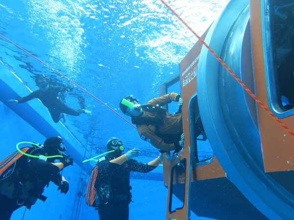 119 항공대원이 비상호흡기를 착용하고 물에 빠진 헬기에서 탈출하는 훈련을 하고 있다. 소방청 제공.