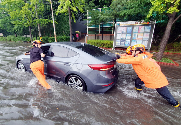 8일 소방관들이 수도권에 내린 폭우로 물에 잠긴 자동차를 끌어내고 있다. 연합뉴스 